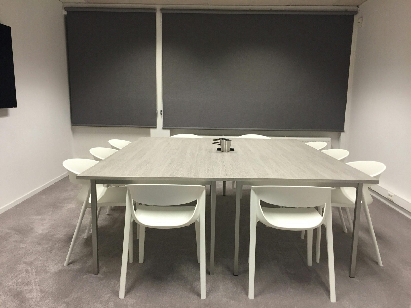 Contemporary minimalist meeting room with modern furniture and gray blinds.